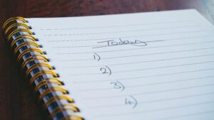 A close-up view of a handwritten to-do list on a spiral notebook with numbers for tasks.