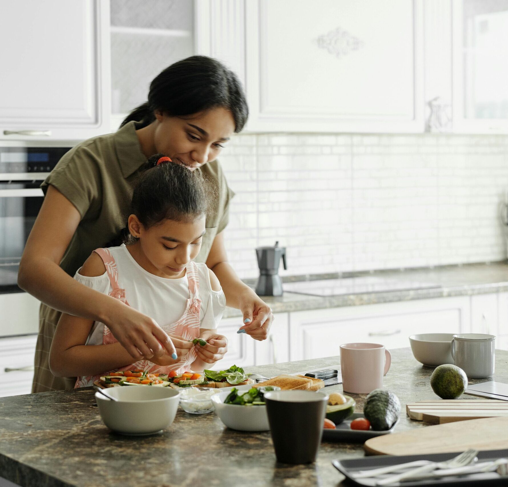 A mom and daughter share a bonding moment while preparing a healthy lunch together in the kitchen.