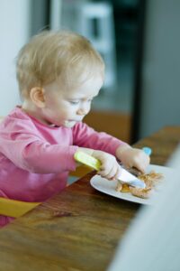 Cute toddler with blonde hair enjoys a meal indoors at home.