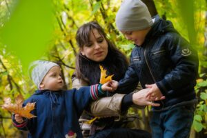 Joyful family moment in park with kids playing among colorful autumn leaves.