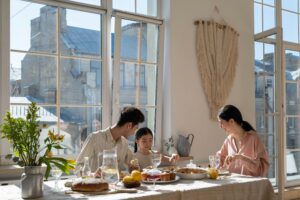 Family of three enjoying a meal together in a sunlit dining room, embracing warmth and togetherness.
